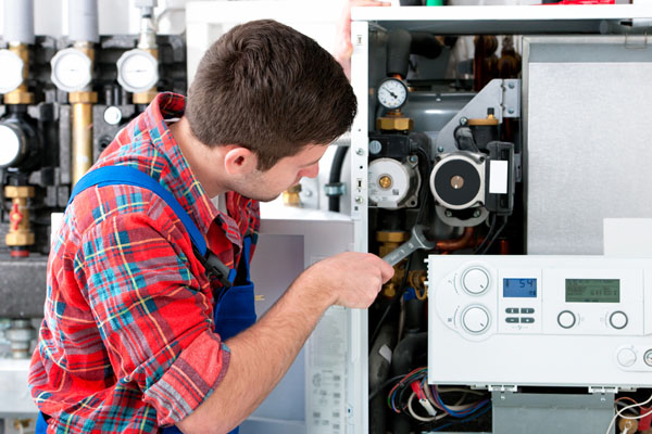 Heating technician repairing boiler controls in Covina