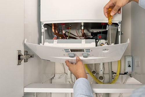 Heating technician repairing a residential boiler in Covina
