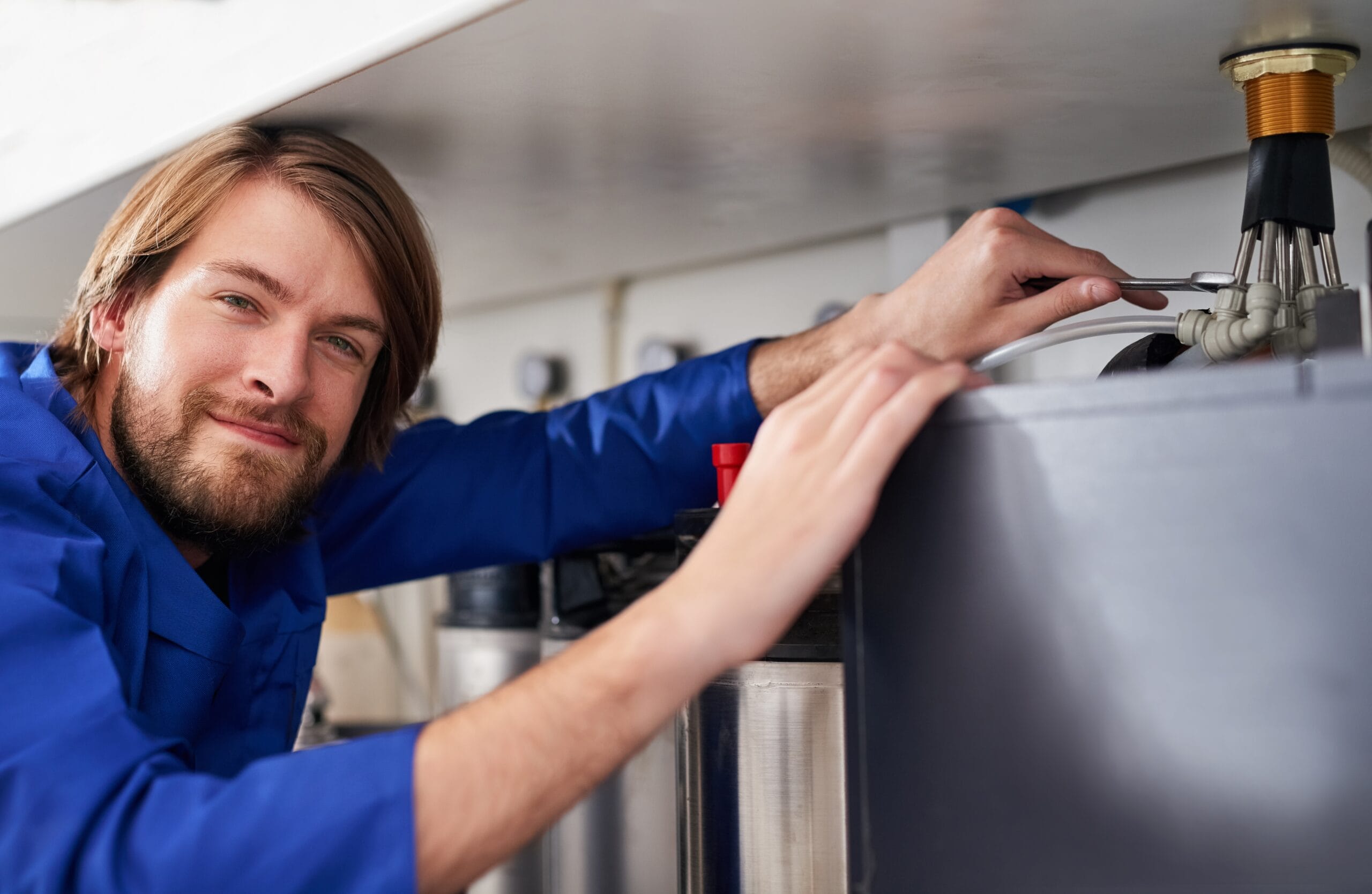 Technician servicing a residential water heater tank in Covina